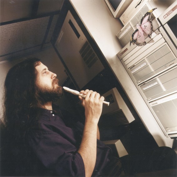 Photo of RMS as a young man playing a flute to a butterfly rested on a server.
